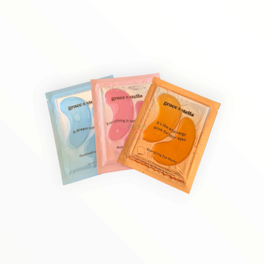 Three Grace by Stella eye mask patches in individual foil packets, shown in light blue, pink, and orange on a clean white background.